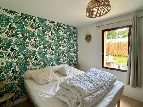 un lit dans une chambre avec un mur végétal dans l'établissement Maison Charme Proche Plage et Forêt avec Jardin, WiFi, BBQ, et Pistes Cyclables à Proximité - FR-1-652-39, à Saint-Jean-de-Monts