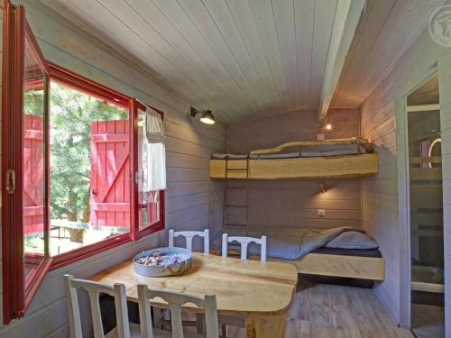Cette petite chambre comprend une table et des lits superposés. dans l'établissement Roulotte du Chat qui Pète: Séjour Paisible et Animaux Bienvenus - FR-1-496-308, à Saint-Germain-Lespinasse