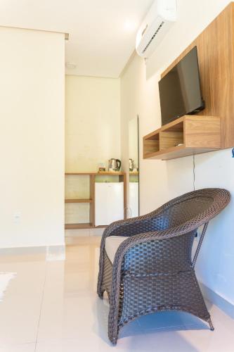 a wicker chair in a living room with a television at Vila da Mata Chalés in Alto Paraíso de Goiás