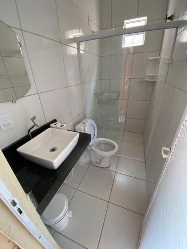 a white bathroom with a sink and a toilet at Chico Caranguejo da Baleia in Itapipoca