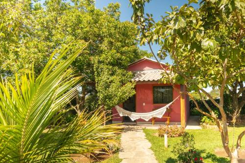 a red house with a hammock in front of it at Vila da Mata Chalés in Alto Paraíso de Goiás