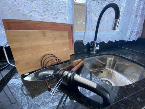 - un comptoir de cuisine avec un évier et un robinet dans l'établissement Casa 3 Condomínio Pé na Areia Ponta do Papagaio, à Palhoça