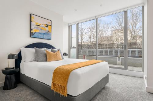 a bedroom with a large bed and large windows at The Alta Apartments by Urban Rest in Sydney