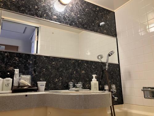 a bathroom with a sink and a mirror at HOTEL LiVEMAX BUDGET Amagasaki in Amagasaki