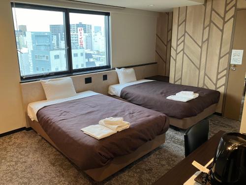 a hotel room with two beds and a desk at HOTEL LiVEMAX BUDGET Amagasaki in Amagasaki