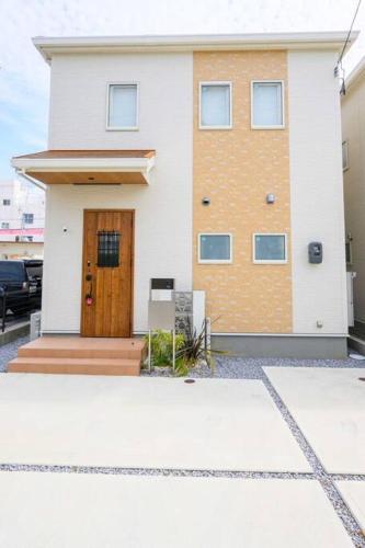 a white house with a brown door on it at Paradiso北谷 in Okinawa City