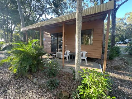 a small wooden cabin with two chairs and a table at 1770 Holiday Village in Seventeen Seventy