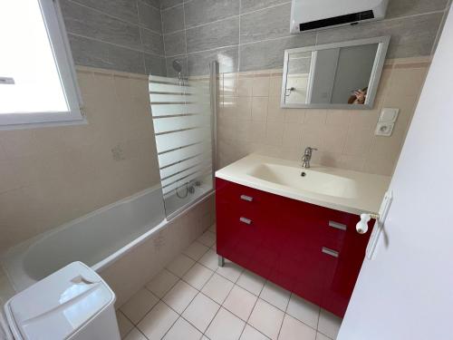 La salle de bains est pourvue d'un lavabo et d'une armoire rouge. dans l'établissement Maison de ville avec jardin, proche plage et commerces, parking privé - La Tranche-sur-Mer - FR-1-22-370, à La Tranche-sur-Mer