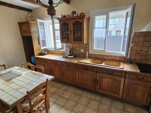 une cuisine avec des armoires en bois, un évier et une table dans l'établissement Maison Plain-Pied à Royan: 3 Chambres, Terrasse, Proche Plages, Calme sur Terrain de 500 m² - FR-1-71-106, à Royan