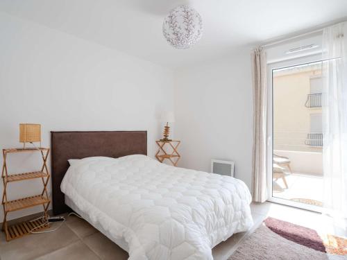 une chambre blanche avec un grand lit et une fenêtre dans l'établissement T3 climatisé neuf, proche plage avec terrasse spacieuse et parking à Narbonne - FR-1-409-272, à Narbonne