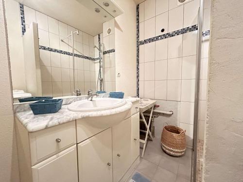 une salle de bain blanche avec un lavabo et un miroir dans l'établissement Sainte-Maxime : T2 calme avec piscine, terrasse, proche plages et commerces - FR-1-226-552, à Sainte-Maxime