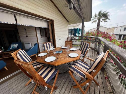 une table et des chaises en bois sur une terrasse dans l'établissement Chalet Spacieux et Confortable à 250m de la Plage avec Wifi et Terrasse à Gruissan - FR-1-784-29, à Gruissan