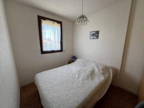 une chambre avec un lit blanc et une fenêtre dans l'établissement Charmant T2 avec loggia, TV, lave-linge, climatisation portative, proche port et plage à Port Leucate - FR-1-81-621, à Leucate