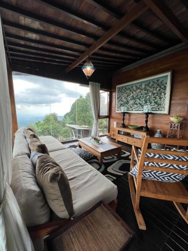 a living room with a couch and a large window at Harvest Palace Munduk in Munduk