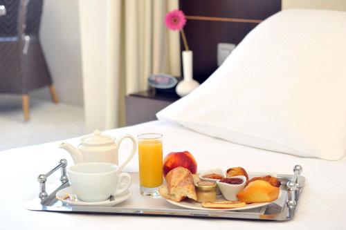 a tray of breakfast food and orange juice on a bed at Mercure Aix-en-Provence La Duranne Gare TGV in Aix-en-Provence