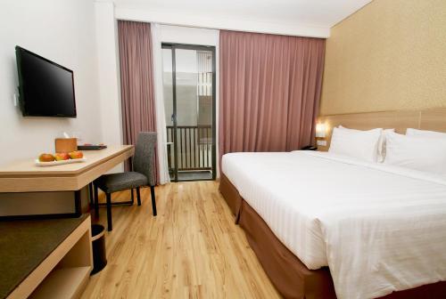 a hotel room with a large bed and a desk with a computer at Swiss-Belhotel Sorong in Sorong