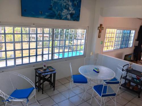 a room with a table and chairs and windows at Casa de playa Shangrilá in Las Palmeras