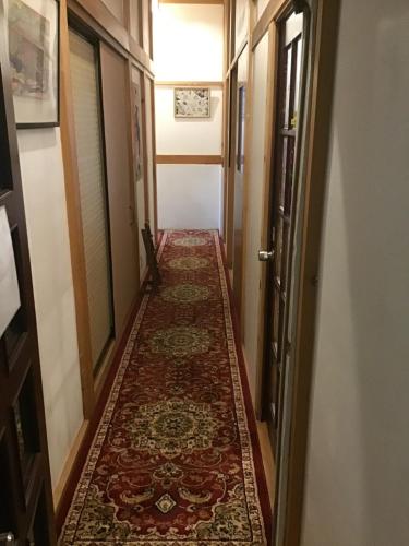 an empty hallway with a carpeted floor and a corridor with doors at COZY Inn Free Shuttle service in Nikko