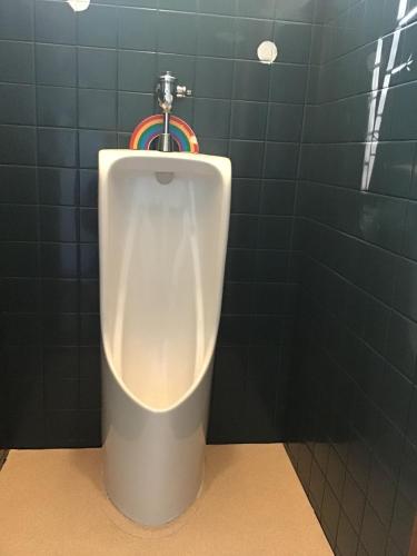 a urinal in a bathroom with a green tiled wall at COZY Inn Free Shuttle service in Nikko