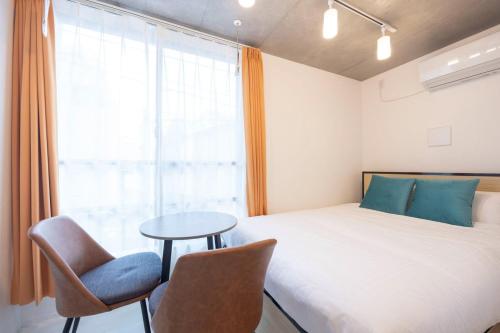 a bedroom with a bed and two chairs and a window at ARUCIA Sangenjaya in Tokyo