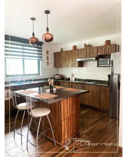 a kitchen with wooden cabinets and a island with bar stools at Departamento Loma-Bonita in Guadalajara