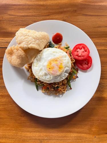 ein weißer Teller mit einem Ei darüber. in der Unterkunft Lime Penida Cottages in Nusa Penida