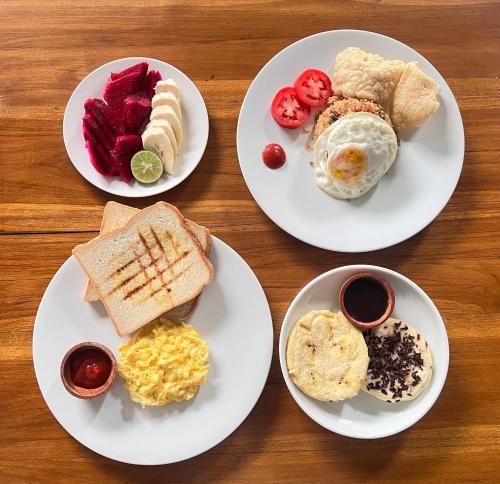 vier Frühstücksteller auf einem Holztisch in der Unterkunft Lime Penida Cottages in Nusa Penida