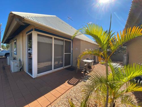 a house with a patio and a palm tree at Osprey Holiday Village Unit 201 1 Bedroom in Exmouth