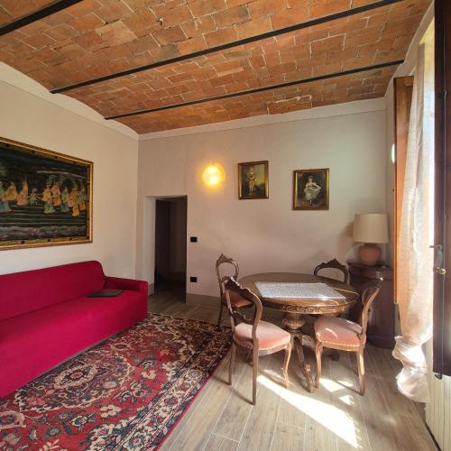 a living room with a red couch and a table at La Rosa Rossa in San Casciano dei Bagni