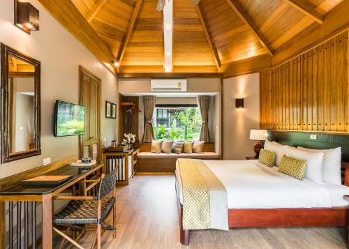 a bedroom with a bed and a desk in a room at River Kwai Resotel in Sai Yok