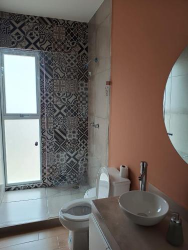 a bathroom with a sink and a toilet and a window at Casa Valeria in Oaxaca City