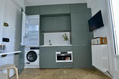 une cuisine avec des armoires vertes et une machine à laver dans l'établissement My Tiny House Paris, à Paris