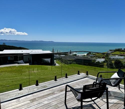 a chair on a deck with a view of the ocean at Doubtless Delight - Cable Bay Holiday Home in Cable Bay