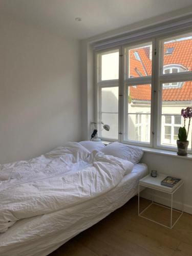 a white bed in a room with a window at Oldest bakery in Denmark 17 min from Airport 5 stars in Copenhagen
