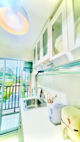 a kitchen with white cabinets and a sink and a window at Sea&Mountain view,5 mins walk to famous beach with King size bed in Hua Hin