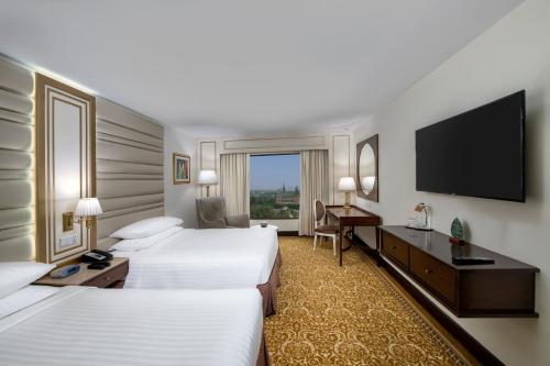 a hotel room with two beds and a flat screen tv at Karachi Marriott Hotel in Karachi