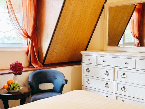 a bedroom with a bed and a chair and a table at TTR Joy Apart' Hotel in Da Lat