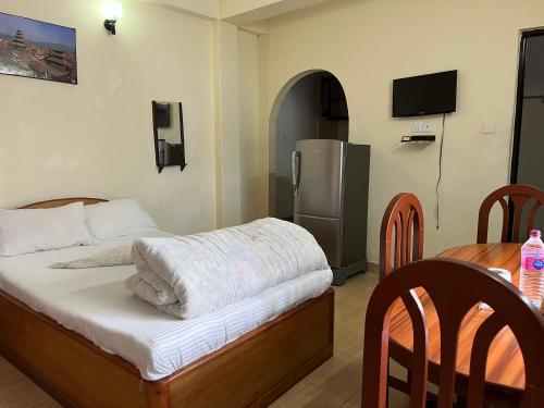 ポカラにあるNew Elite’s guest houseのベッドルーム1室(ベッド1台、テーブル、冷蔵庫付)