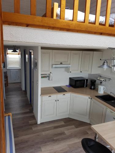une cuisine avec des armoires blanches et un comptoir dans l'établissement residence des plages, à Guidel