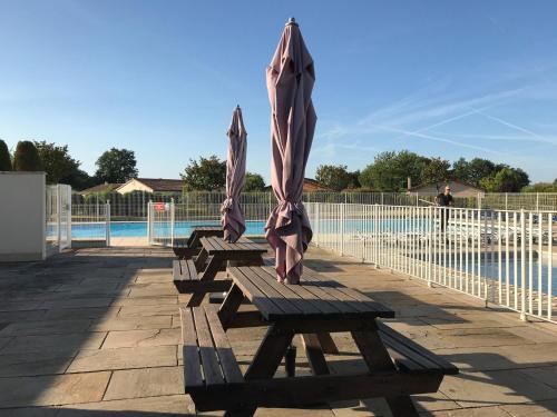 three wooden benches with umbrellas next to a pool at Villa in Les Forges with Golf & Pool Access in Les Forges