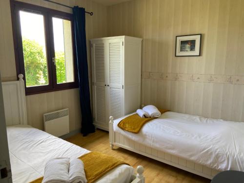 a bedroom with two beds and a window at Terre et Mer, maison avec jardin in Quend