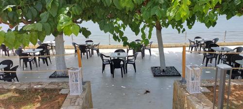 a group of tables and chairs under trees at Senia Holidays in Preveza