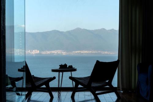 a room with a table and chairs and a view of the ocean at 慢境Slow Land半山海景花园酒店 in Dali