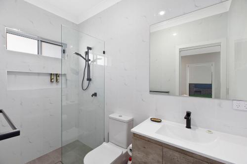 a bathroom with a toilet and a sink and a shower at Sandy Feet Retreat in The Entrance