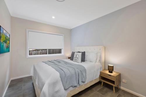 a white bedroom with a bed and a window at Sandy Feet Retreat in The Entrance