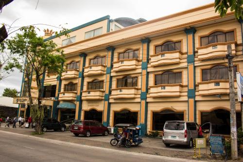 a large building with cars parked in front of it at Crown Royale Hotel in Balanga