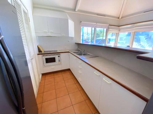 a kitchen with white cabinets and a sink at Osprey Holiday Village Unit 112 in Exmouth