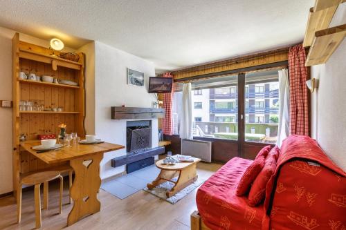 un salon avec un canapé rouge et une table dans l'établissement Appartement Central Des Houches - 15 - Happy Rentals, aux Houches