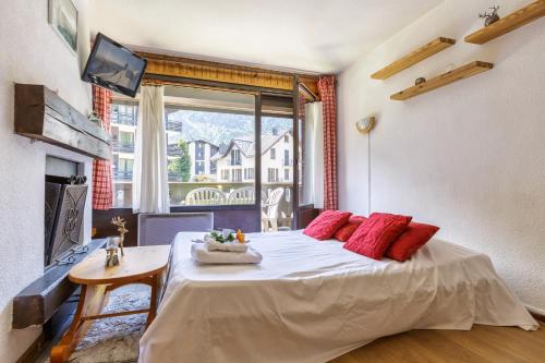une chambre avec un lit avec des oreillers rouges et une fenêtre dans l'établissement Appartement Central Des Houches - 15 - Happy Rentals, aux Houches