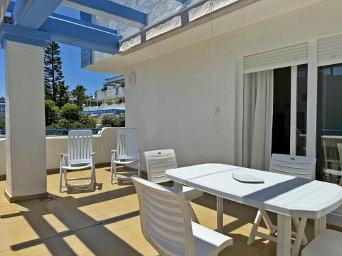 Une table à manger et des chaises blanches sont disponibles sur la terrasse. dans l'établissement Apartamento Playa Ballena - Ole Solutions, à Costa Ballena